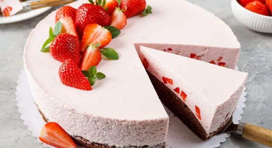 Ein köstlicher Erdbeer Schmand Kuchen in Springform, dekoriert mit frischen Erdbeeren und Minze. Ein Stück wurde bereits entnommen.