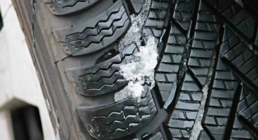 Gomme invernali con neve e ghiaccio incastrati nel battistrada. Le gomme screpolate battistrada mostrano segni di usura, ma ancora funzionali.