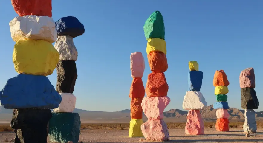 Les **seven magic mountains** illuminent le désert. Des rochers colorés empilés créent une œuvre d'art vibrante sous un ciel bleu.