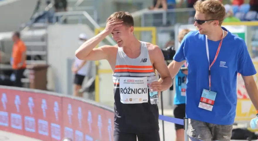 Krzysztof Różnicki, lekkoatleta, po biegu z dłonią na czole, obok niego stoi mężczyzna w niebieskiej koszulce.