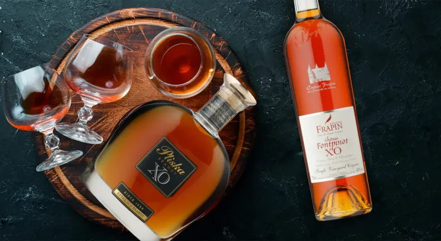 Brandy vs Cognac: butelka Pliska XO Brandy i Frapin Fontpinot XO Cognac, dwa kieliszki z bursztynowym trunkiem.