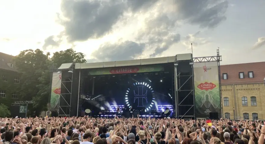 Ein riesiges Publikum feiert beim Citadel Music Festival in Berlin. Die Bühne ist beleuchtet, die Menge jubelt.