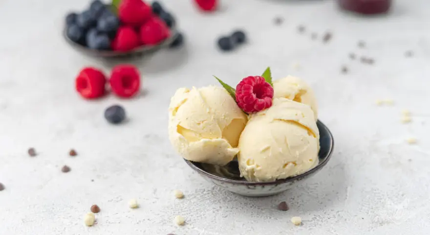 Cremiges Vanilleeis, garniert mit einer Himbeere. Perfekt, um eis ohne zucker selber machen zu lernen.