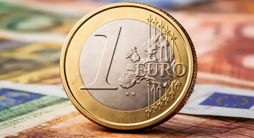 Une pièce de 1 euro 1999, bicolore, posée sur des billets en euros.