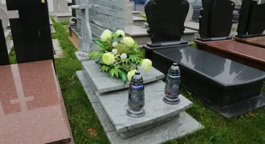 Kwiaty i znicze na kamiennej płycie grobu to sposób, jak udekorować grób bez pomnika.