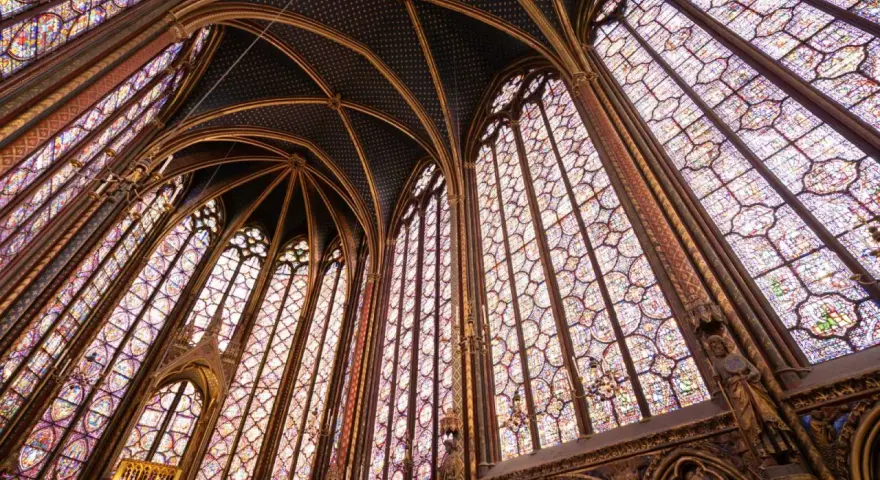 Interior de una capilla con vidrieras de colores y bóvedas ojivales, un ejemplo impresionante del estilo gótico.