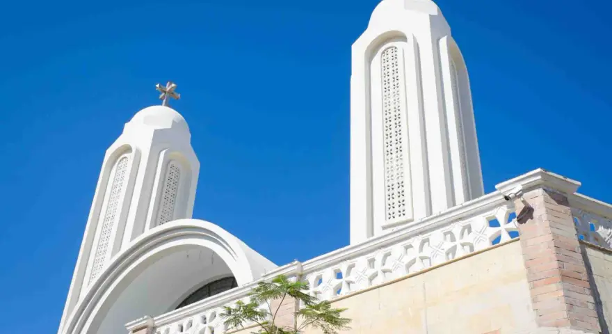 Białe wieże kościoła pod błękitnym niebem. Idealna pogoda w Egipcie w sierpniu, by podziwiać architekturę.