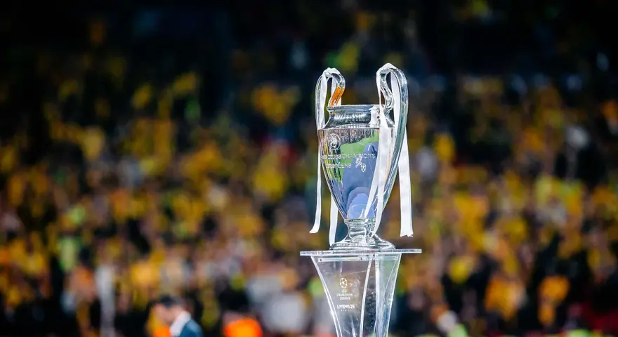 Trofeum Ligi Mistrzów na podium, z tłumem kibiców w tle. Zastanawiasz się, ile za wygranie ligi mistrzów?