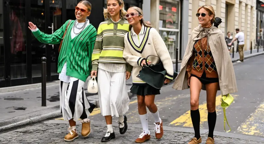 Cztery kobiety w modnych, sportowych stylizacjach idą ulicą, prezentując buty.