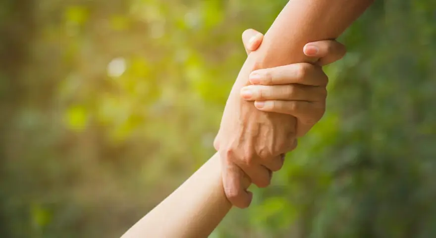 Zwei Hände greifen ineinander, ein Symbol für **Altruismus** und gegenseitige Hilfe im sanften Licht.