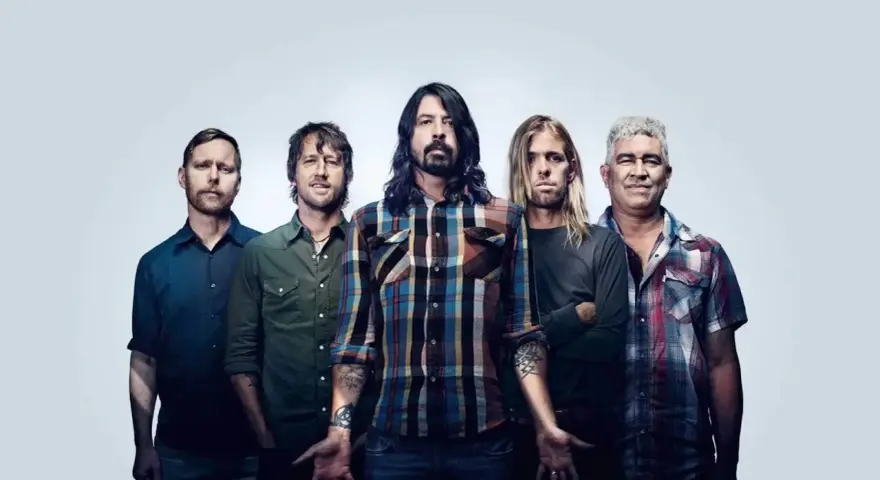 Les membres de Foo Fighters posent ensemble, cinq hommes aux regards intenses, prêts à enflammer la scène.