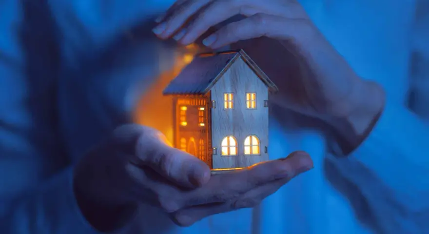 Mains tenant une maisonnette illuminée, symbolisant la jurisprudence logement de fonction et la protection du foyer.