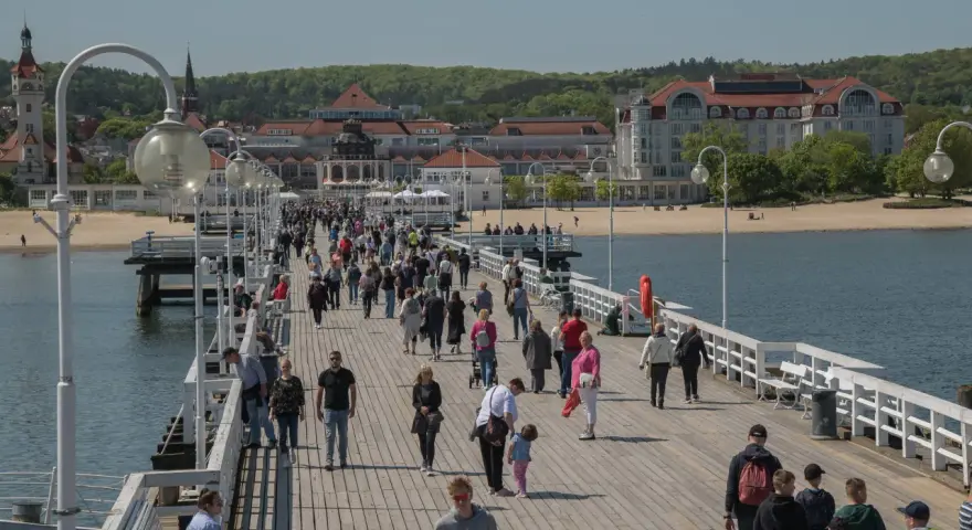 Spacer po molo w Sopocie, gdzie tłumy ludzi korzystają z uroków Bałtyku. To idealne miejsce na relaks i odkrywanie gdańskich atrakcji dla dorosłych.
