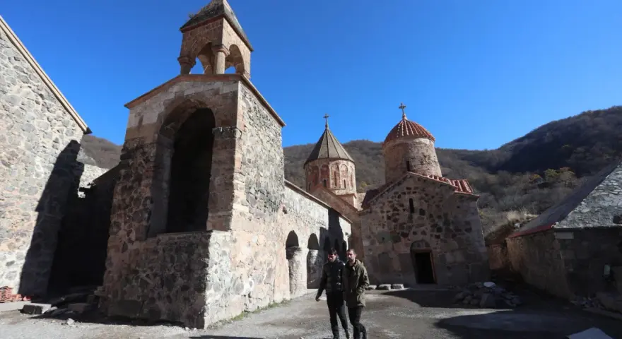 Kamienny klasztor w Armenii, świadectwo bogatej historii i religii. Dwóch mężczyzn spaceruje po dziedzińcu.