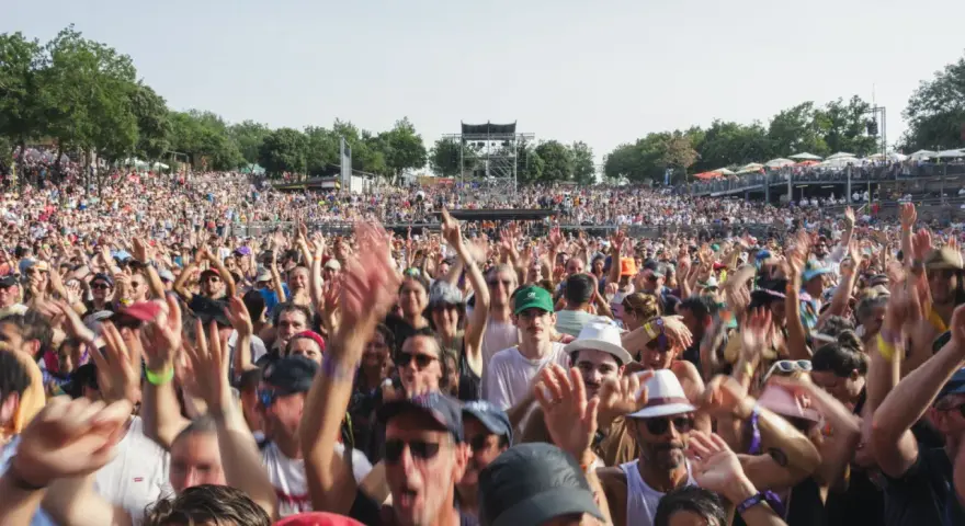 Foule en délire à un concert, mains levées. Certains portent un bouchon oreille sifflement pour se protéger du bruit assourdissant.