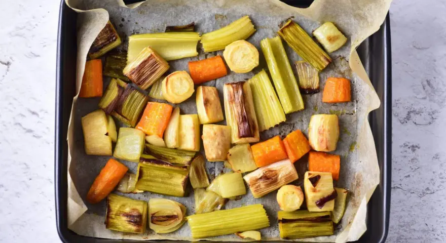 Pokrojone w kawałki marchewki, por i seler przygotowane do pieczenia. Idealne do aromatycznego rosół z pieczonych warzyw.