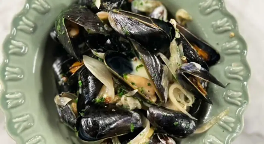 En skål med ångade musslor med lök och persilja. Ett enkelt och gott musslor recept.