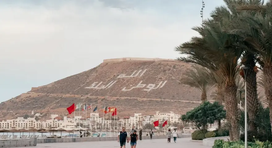 Spacerem po promenadzie w Agadirze, z widokiem na miasto i napisem na wzgórzu. Czy Agadir jest bezpieczny? Tak, wygląda na spokojne miejsce.