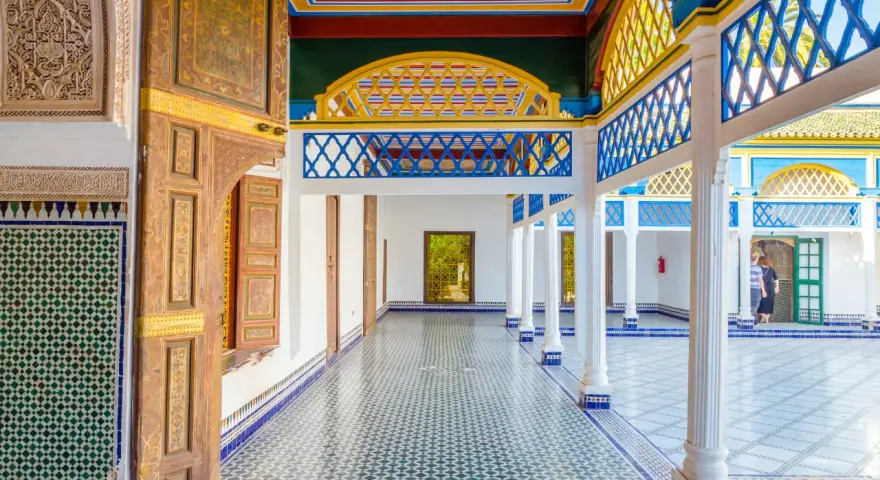 Kolorowy dziedziniec w Maroko, Marrakesz. Wzory geometryczne na ścianach i podłodze, zdobione drzwi i kolorowy sufit.
