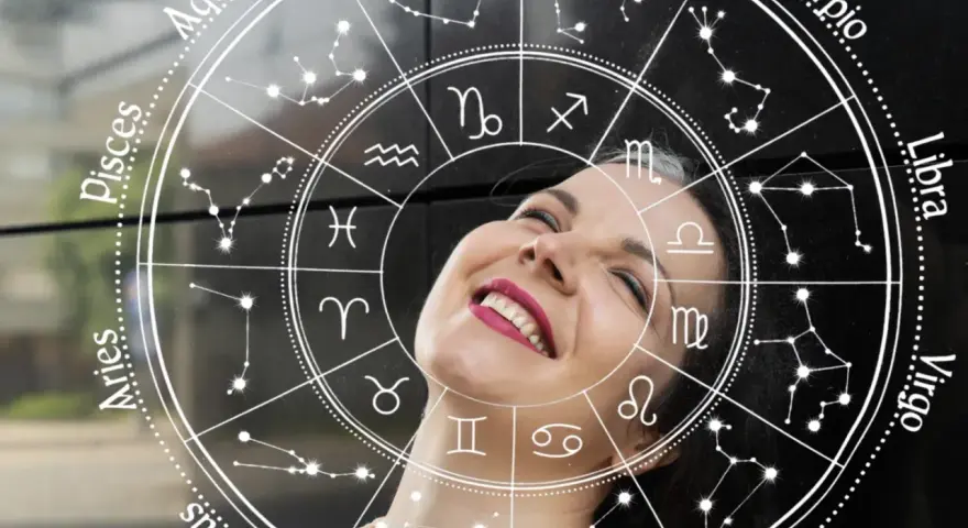 Uśmiechnięta kobieta wpatrzona w koło zodiaku. Sprawdź swój horoskop dzienny Baran i odkryj, co przyniesie Ci dzień!