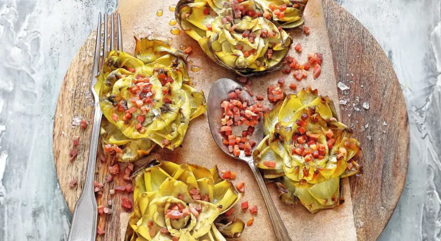 Deliciosas alcachofas al horno, doradas y rellenas de trocitos de jamón, listas para disfrutar.