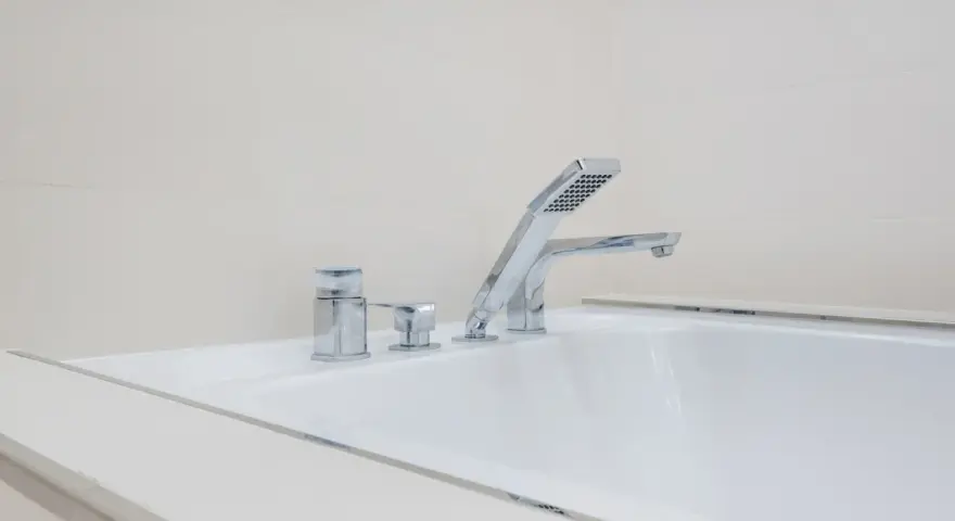 Elegancka bateria wannowa jednootworowa z chromowanymi elementami i słuchawką prysznicową, idealna do nowoczesnej łazienki.