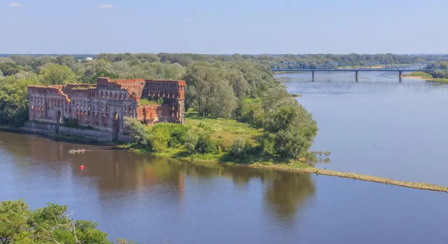 Ruiny twierdzy nad Wisłą, gdzie można poczuć się jak w górach, choć to nie są jakie góry są najbliżej Warszawy. W oddali błękitny most.
