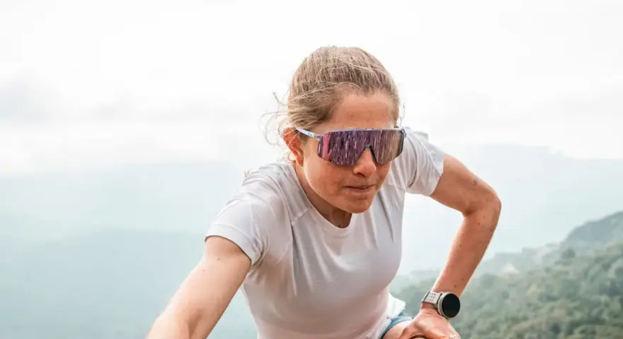 Mujer con gafas de correr, concentrada en su ascenso por la montaña.