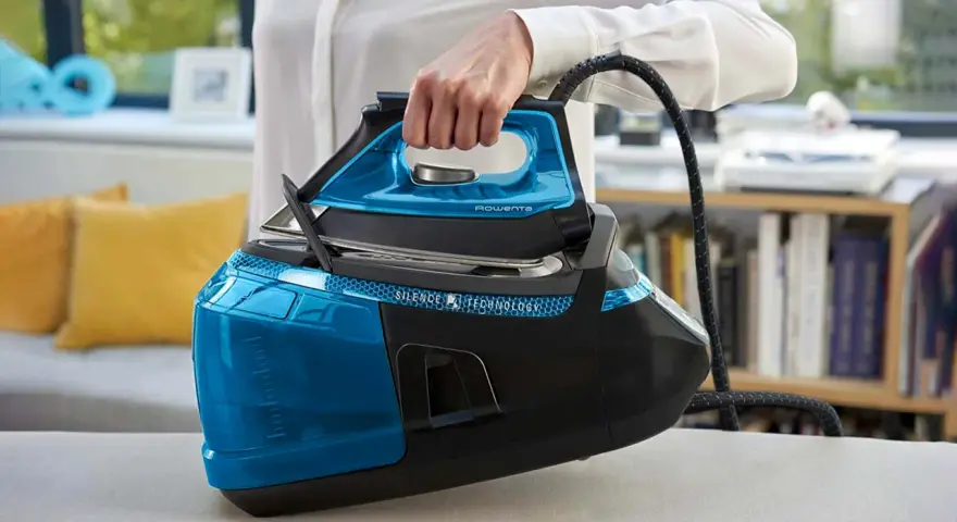 Mano che solleva un ferro da stiro moderno blu e nero, con serbatoio trasparente e tecnologia Silence.