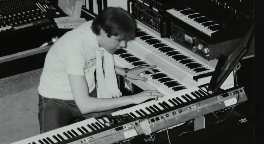 Mann spielt auf mehreren Synthesizern, die typische Klänge der 80er Jahre erzeugen.