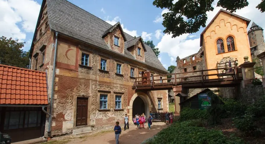 Zamek Książ i jego okolice to jedne z najpiękniejszych wałbrzych atrakcje. Drewniany most łączy zabytkowe budynki, a dzieci zwiedzają teren.