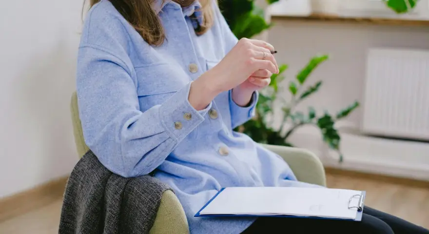 En psykolog sitter med en penna och anteckningsblock, redo att hjälpa någon att hantera ångest.