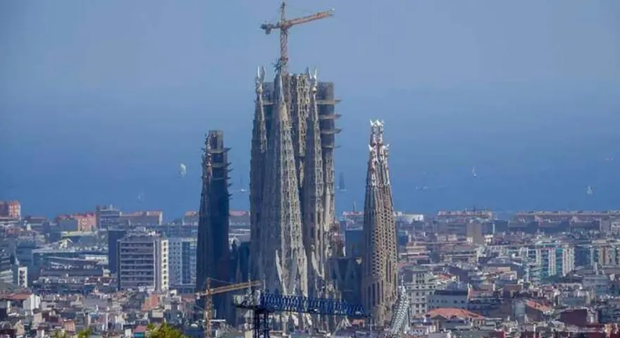 La Sagrada Familia, en plein temps de construction, domine le paysage urbain de Barcelone. Des grues témoignent de l'évolution de ce chef-d'œuvre architectural.