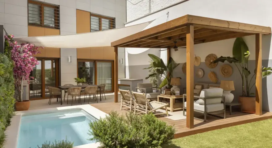 Modernos patios con piscina, zona de estar bajo pérgola de madera y comedor exterior.