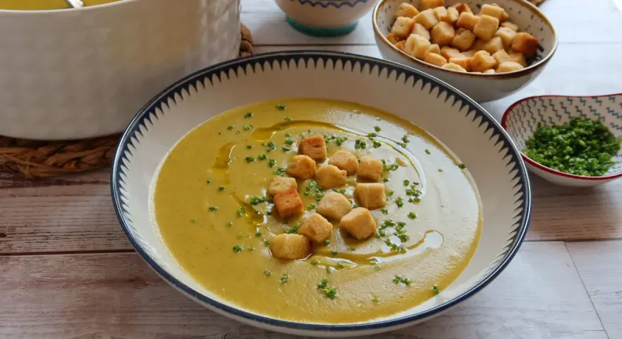 Un cremoso puré de verduras, adornado con picatostes crujientes y un chorrito de aceite de oliva.