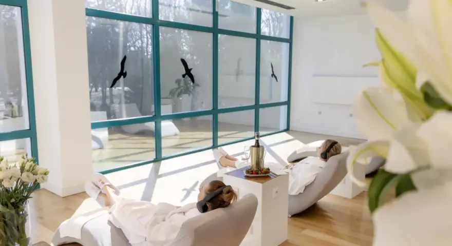 Relaks w spa, idealne **ciechocinek atrakcje na weekend**. Dwie kobiety w szlafrokach odpoczywają na leżakach, słuchając muzyki.