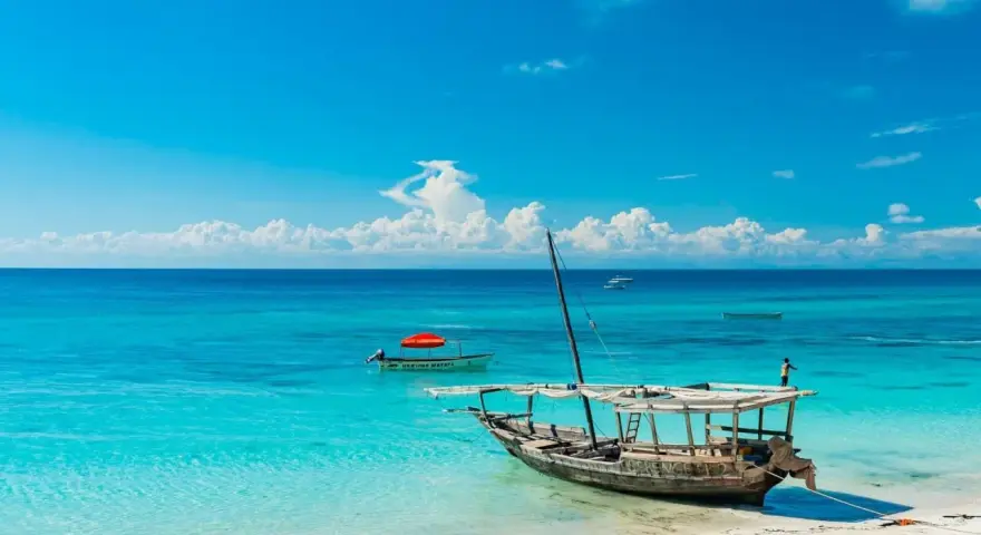 Piękna plaża na Zanzibarze, turkusowa woda, łodzie i marzenia o wakacjach. Może nawet o zarobieniu tam zanzibar dolary.