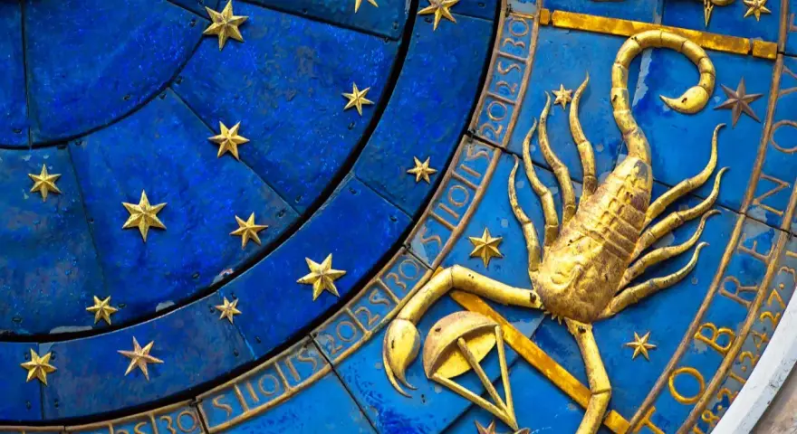 Złoty skorpion, symbol zodiaku, na niebieskiej tarczy z gwiazdami i cyframi.