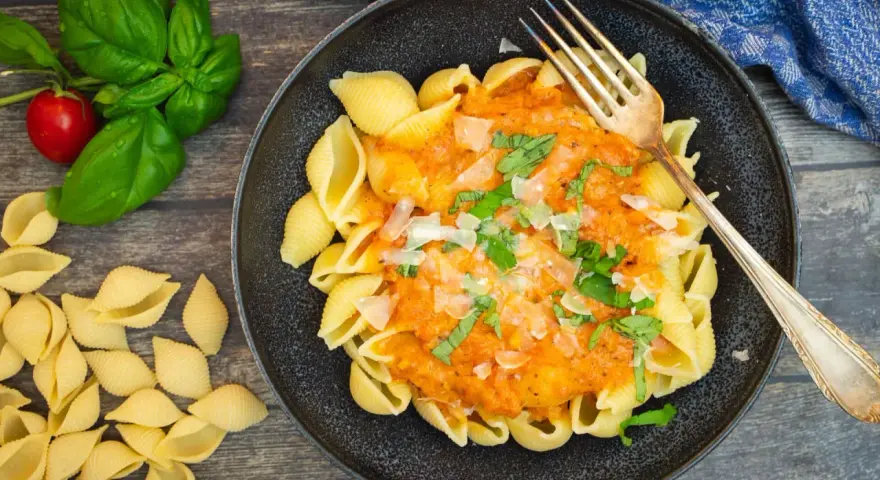 Schalen-Nudeln mit cremiger Tomaten-Sahne-Sauce, garniert mit Basilikum und Parmesan. Ein köstliches Gericht, das zum Genießen einlädt.