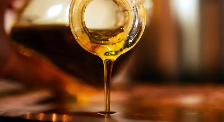 Olio d'oliva dorato cola da una bottiglia. Scopri come conservare l'olio di oliva per mantenerne intatto il sapore.