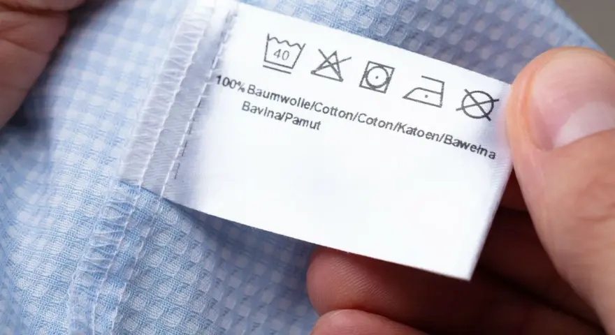 Metka z symbolami prania: prać w 40°C, nie wybielać, prasować, nie wirować symbol. 100% bawełna.
