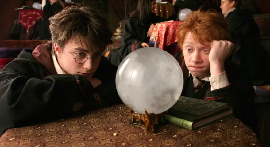 Harry i Ron wpatrują się w wirującą mgłę kryształowej kuli, która mówi, szukając odpowiedzi na lekcji wróżbiarstwa.
