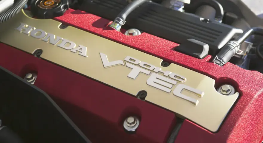 Złota pokrywa silnika Honda z napisem VTEC, otoczona czerwonym, błyszczącym wykończeniem.