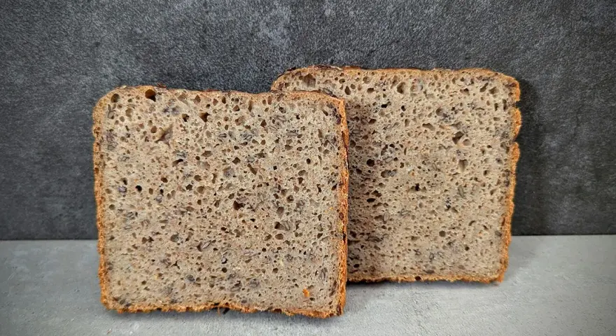 Zwei Scheiben rustikales Vollkornbrot, perfekt für Brot backen ohne Form. Die Kruste ist knusprig, die Krume luftig und voller Körner.