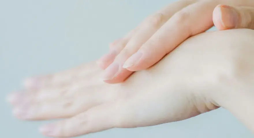 Två händer, en över den andra, med fokus på fingrarna. Huden ser torr ut, vilket kan tyda på eksem på fingrarna.