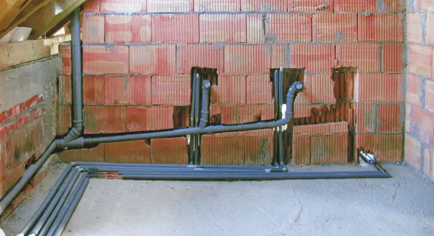 Instalacja hydrauliczna w trakcie budowy, widoczne rury kanalizacyjne i wodne. To kluczowy etap, by wiedzieć, jak zrobić odpowietrzenie WC.
