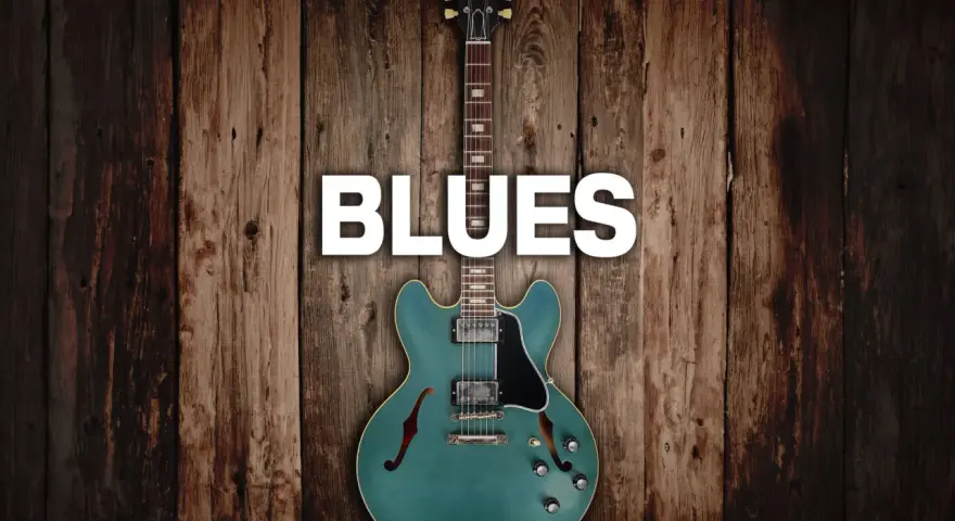 Eine teal-farbene E-Gitarre mit dem Wort "BLUES" darüber, auf rustikalem Holz Hintergrund.