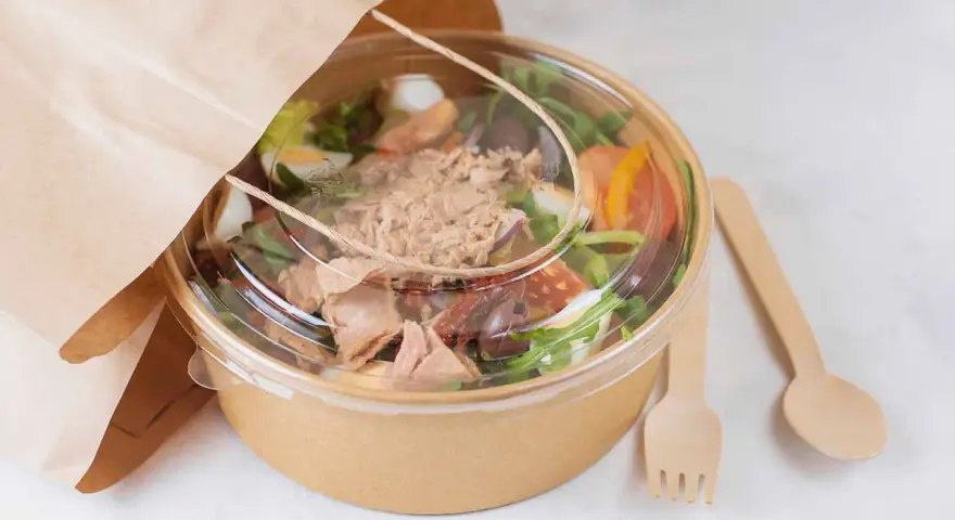 Ensalada de atún para llevar, con ingredientes frescos y cubiertos en un recipiente ecológico. Perfecta para tu licencia take away.