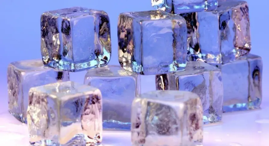 Eiswürfel stapeln sich, glitzernd und durchscheinend. Sie zeigen, wie kalt Eis werden kann, mit gefrorenen Einschlüssen und scharfen Kanten.