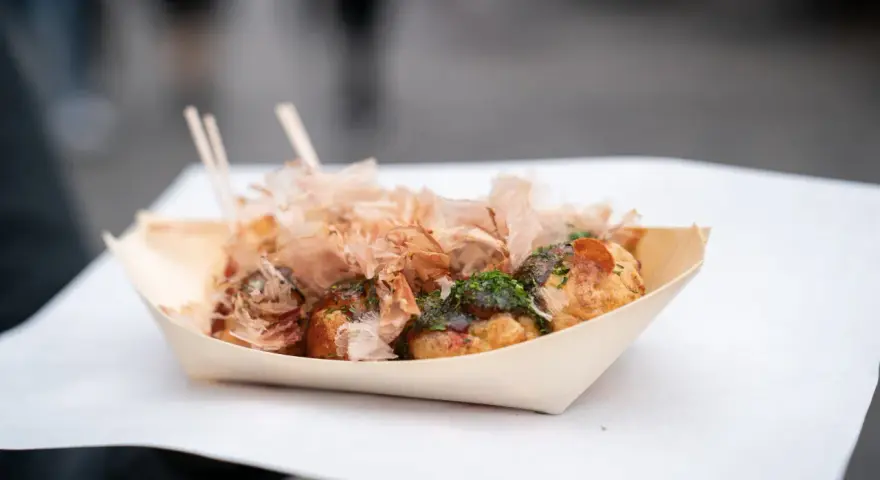 Pyszne takoyaki, czyli japońskie kulki z ośmiornicą, posypane płatkami bonito i zieloną posypką. Idealny japoński street food na wynos.